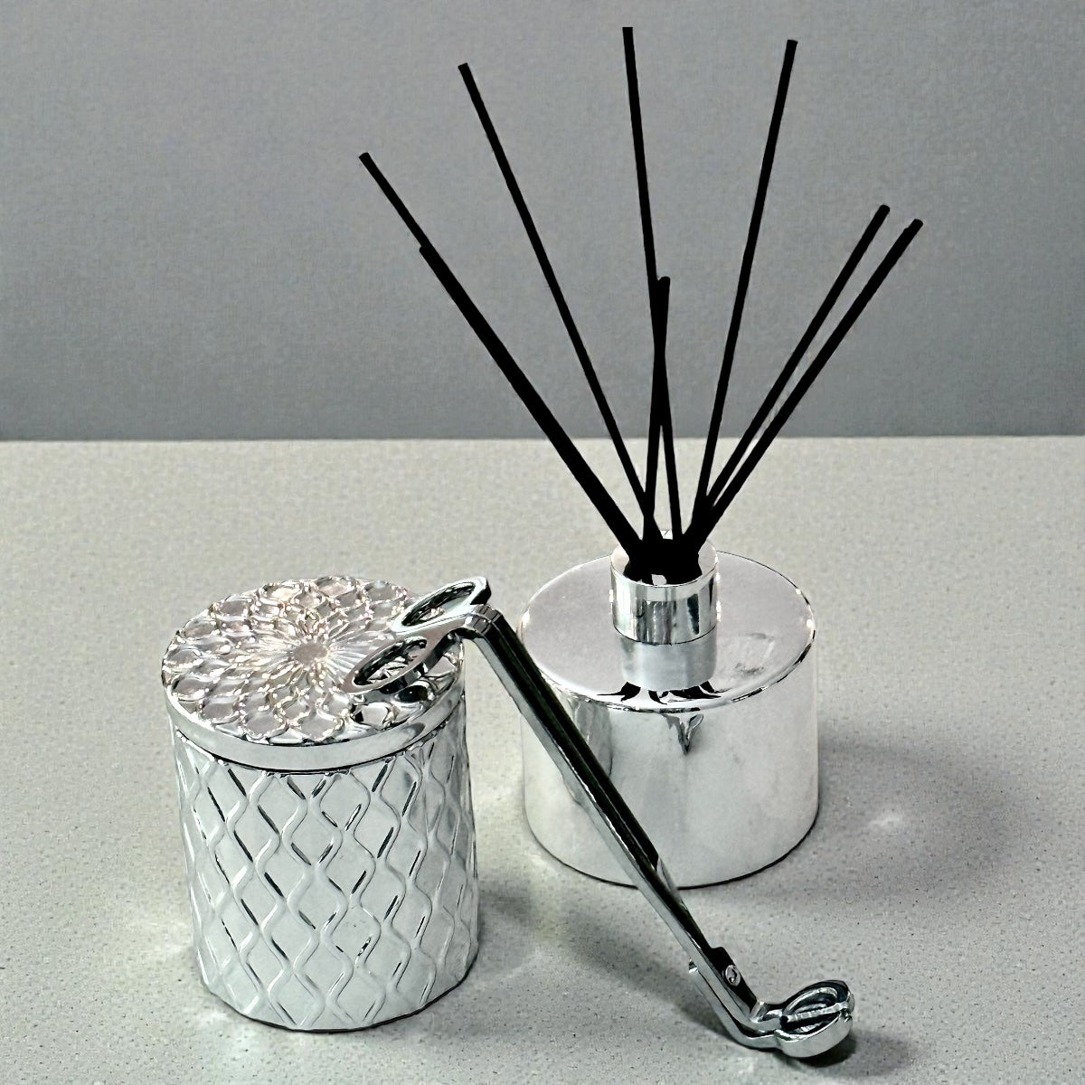 Silver diffuser with black reeds on a gray background