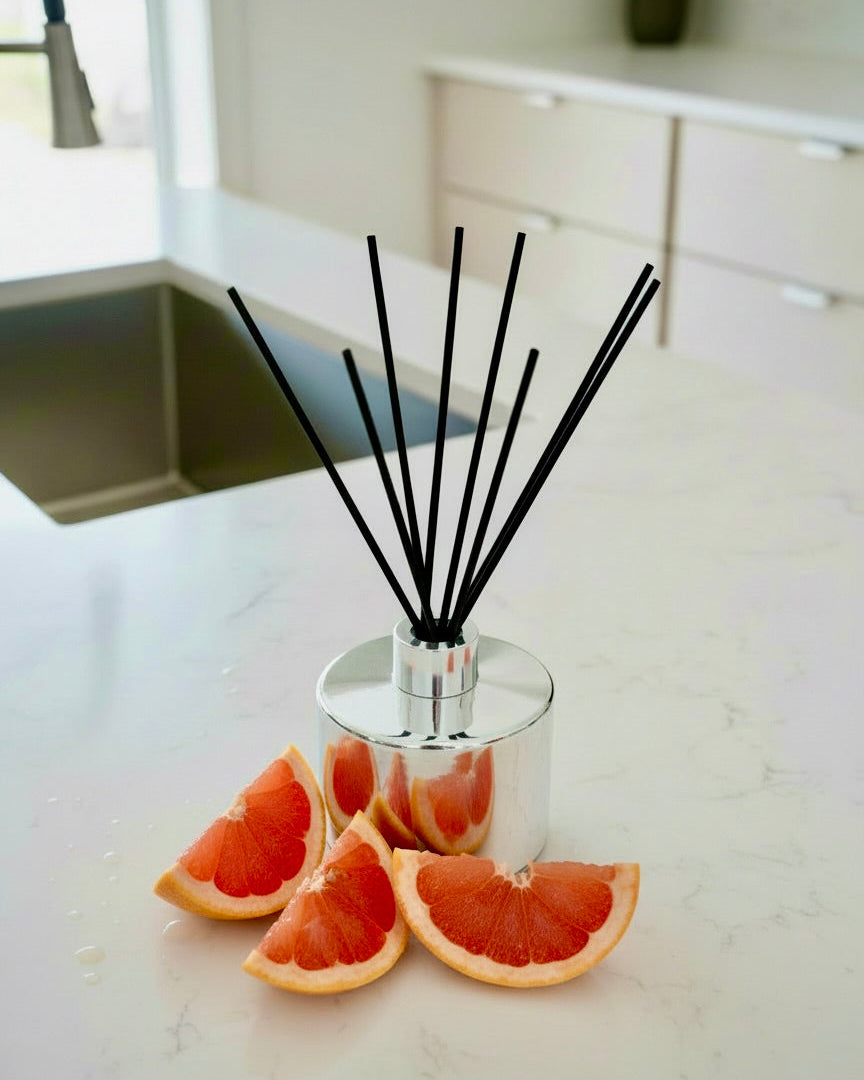 Diffuser with black sticks on a kitchen counter with grapefruit slices