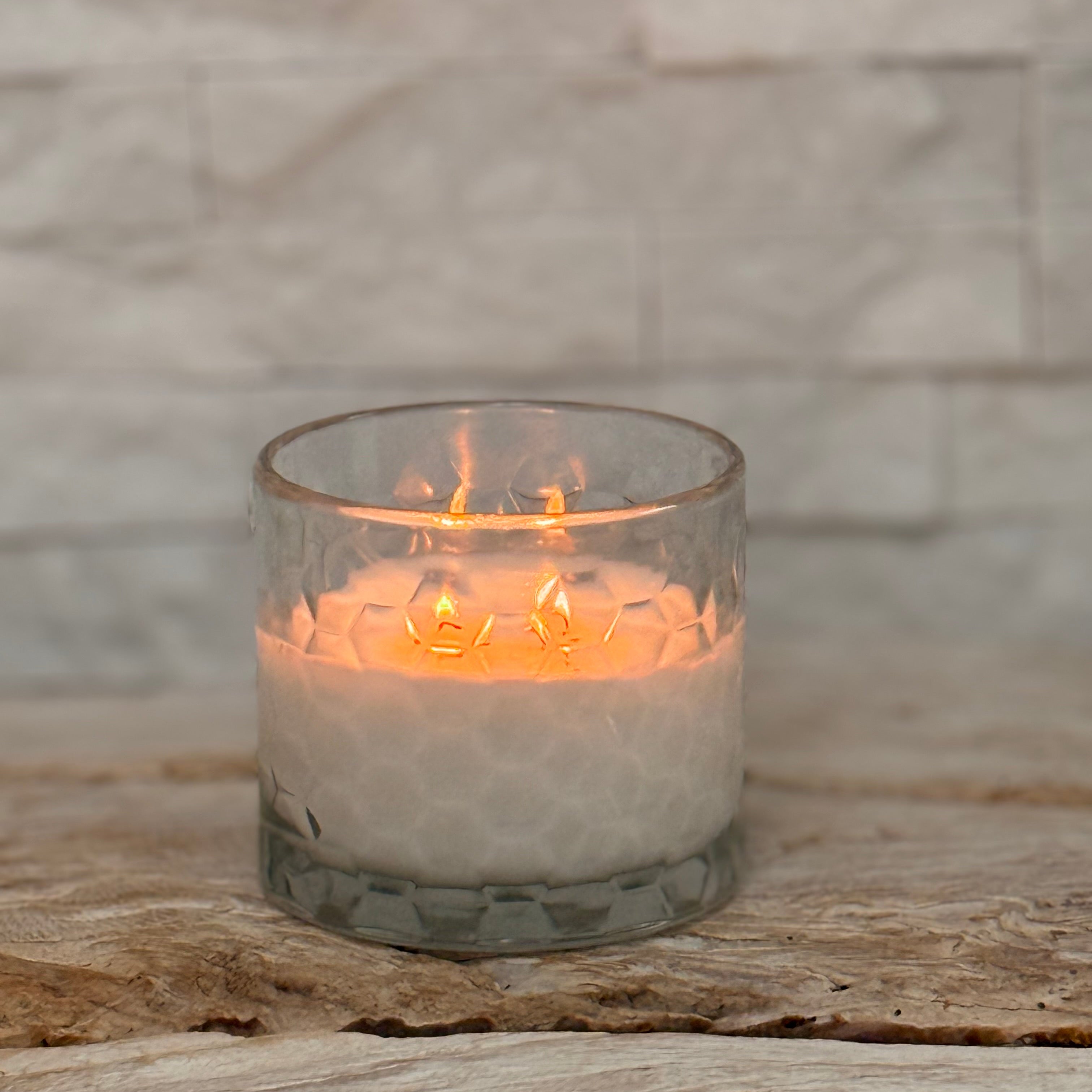 Candle in a glass holder on a stone surface with a stone wall background