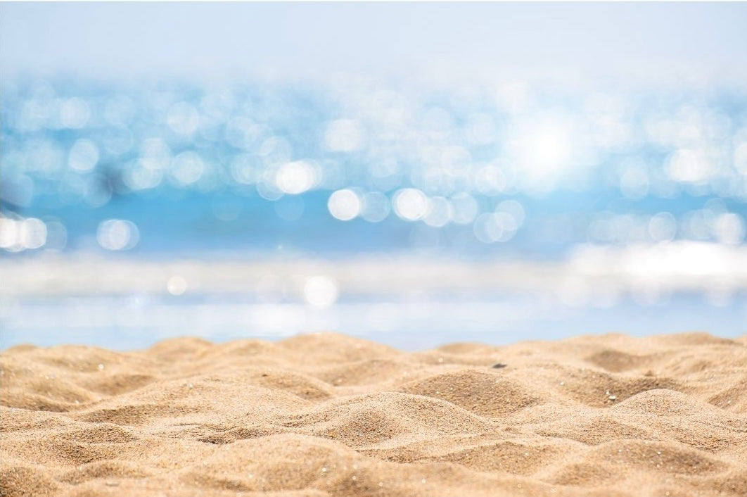 Sandy beach with shimmering water representing Coastal Essence scent