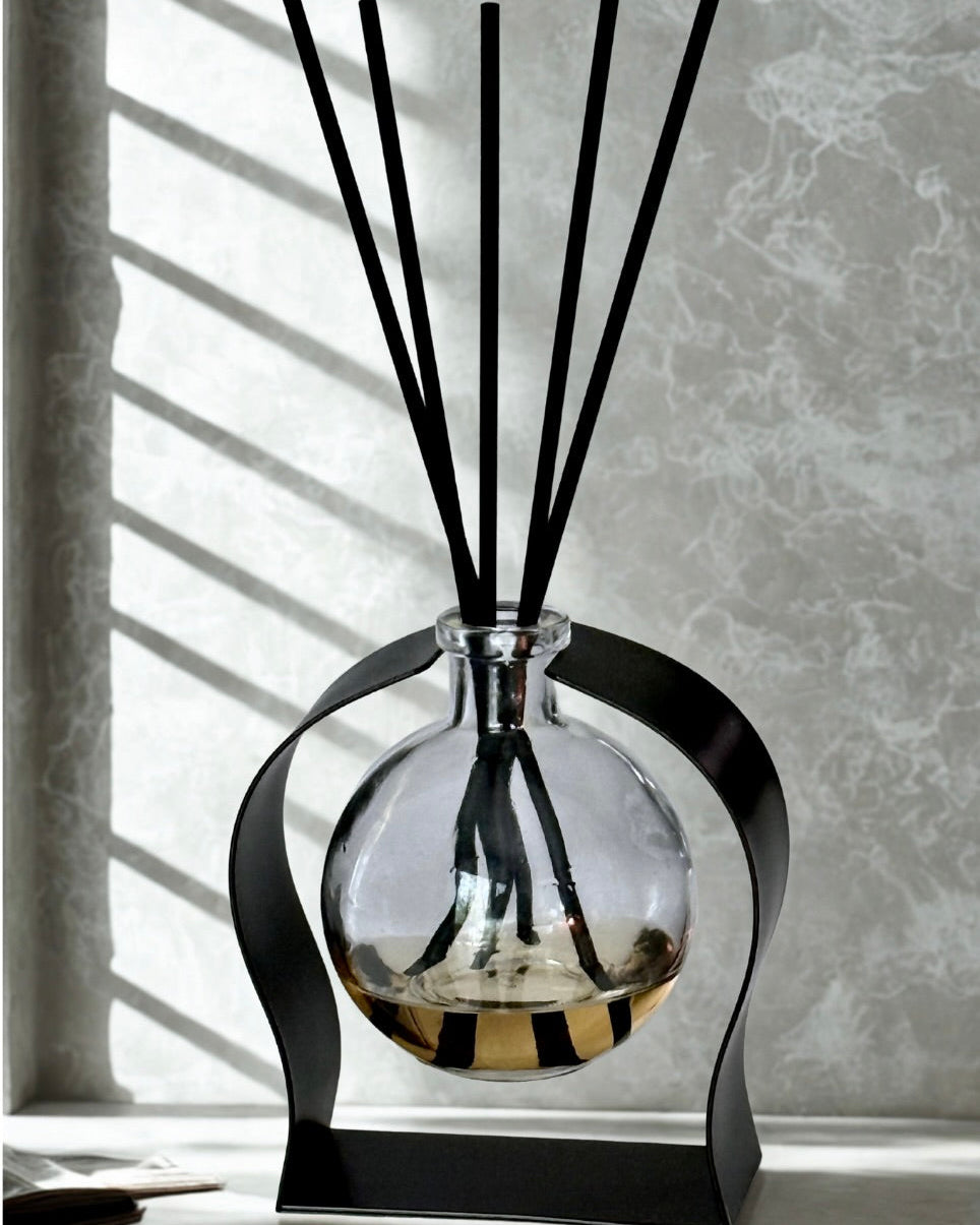 Aromatherapy diffuser with black sticks in a clear glass bottle on a light background