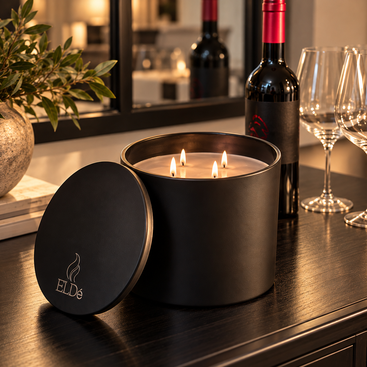 Close-up of the ELDé Fireplace Candle showing four wicks, matte-black vessel, and matching branded lid beside a wine bottle.