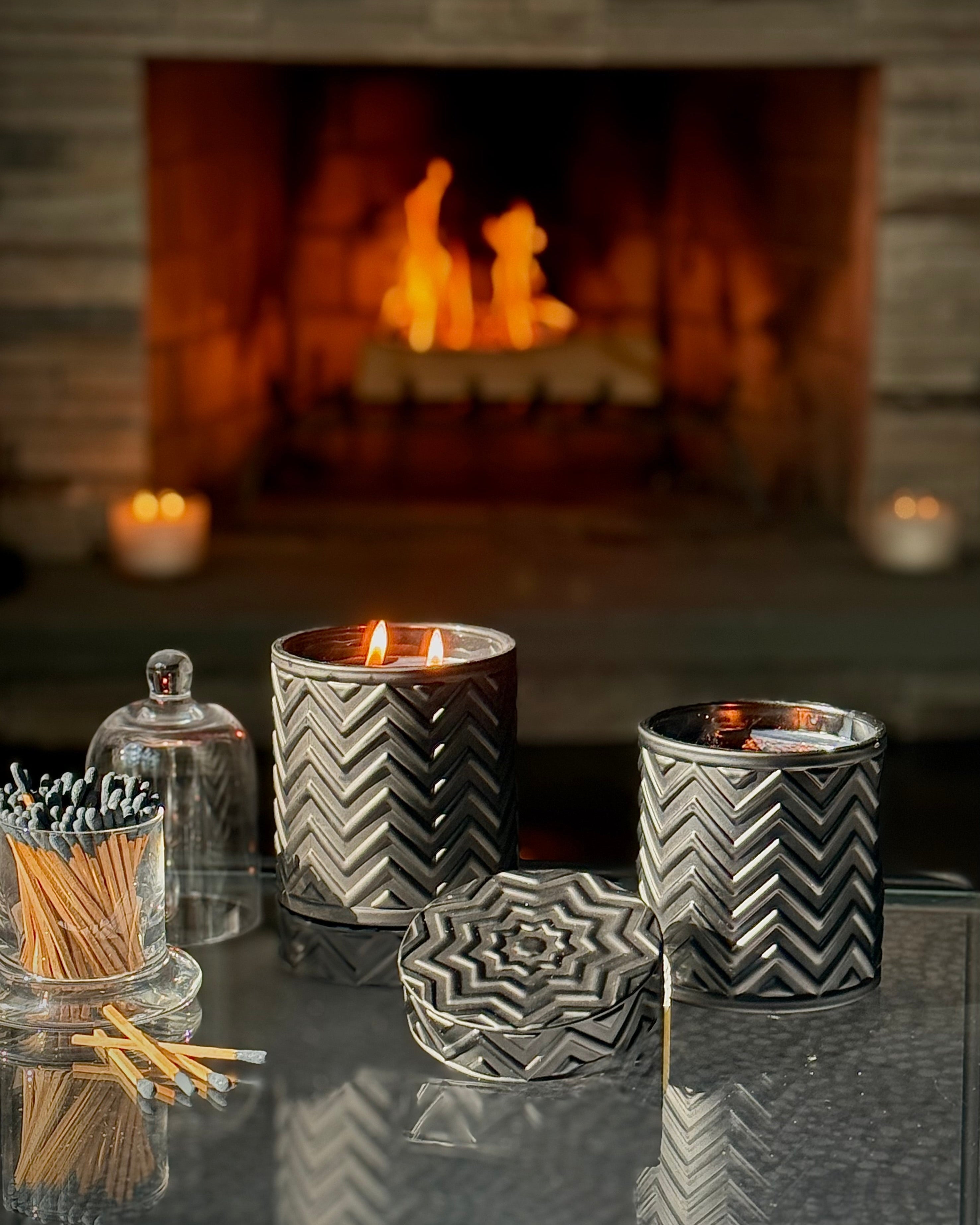 Ember’s Embrace candle from the Onyx Moon collection, glowing softly on a modern table with cozy autumn décor.