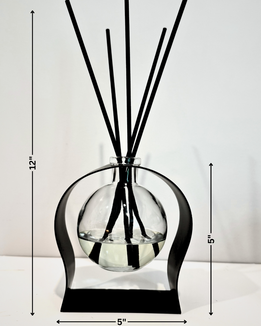 Diffuser with black sticks and glass container on a white background