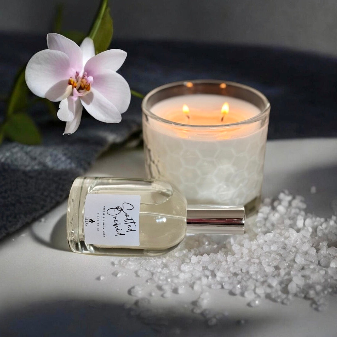 Candle and perfume bottle with a flower on a textured surface