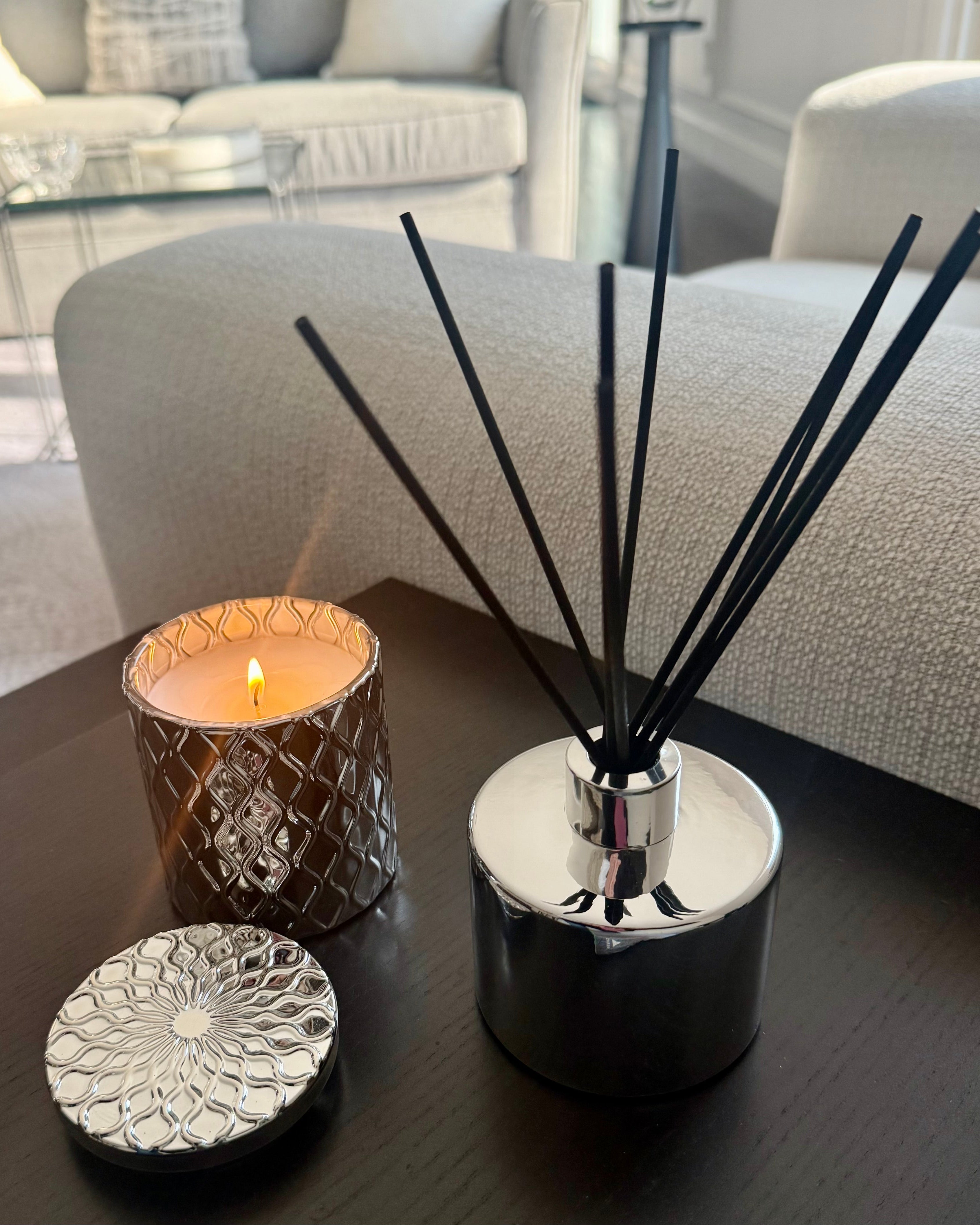 Candle and diffuser on a table with a blurred living room background