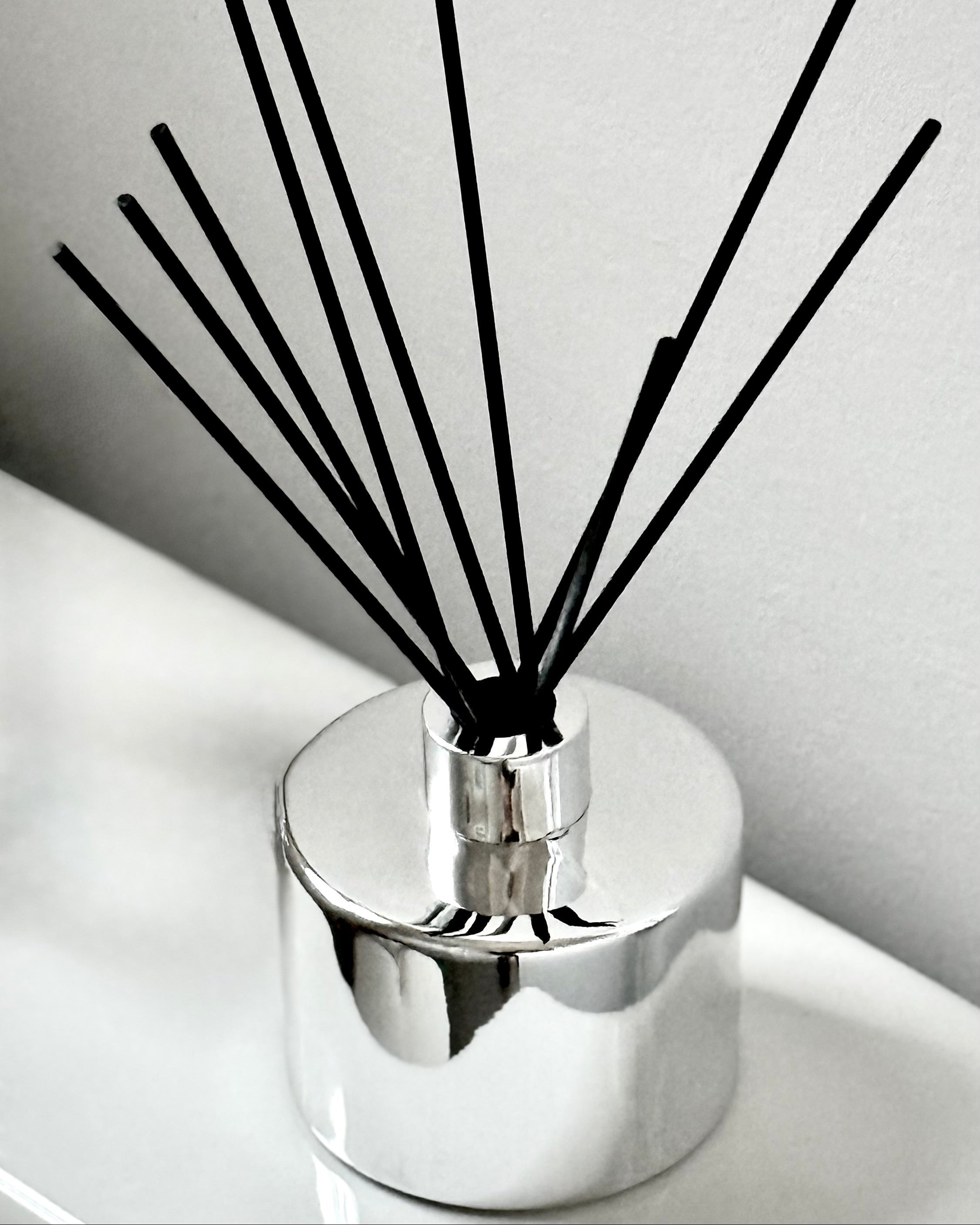 Chrome diffuser with black sticks on a white surface