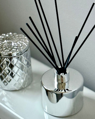 Silver diffuser with black reeds on a white surface