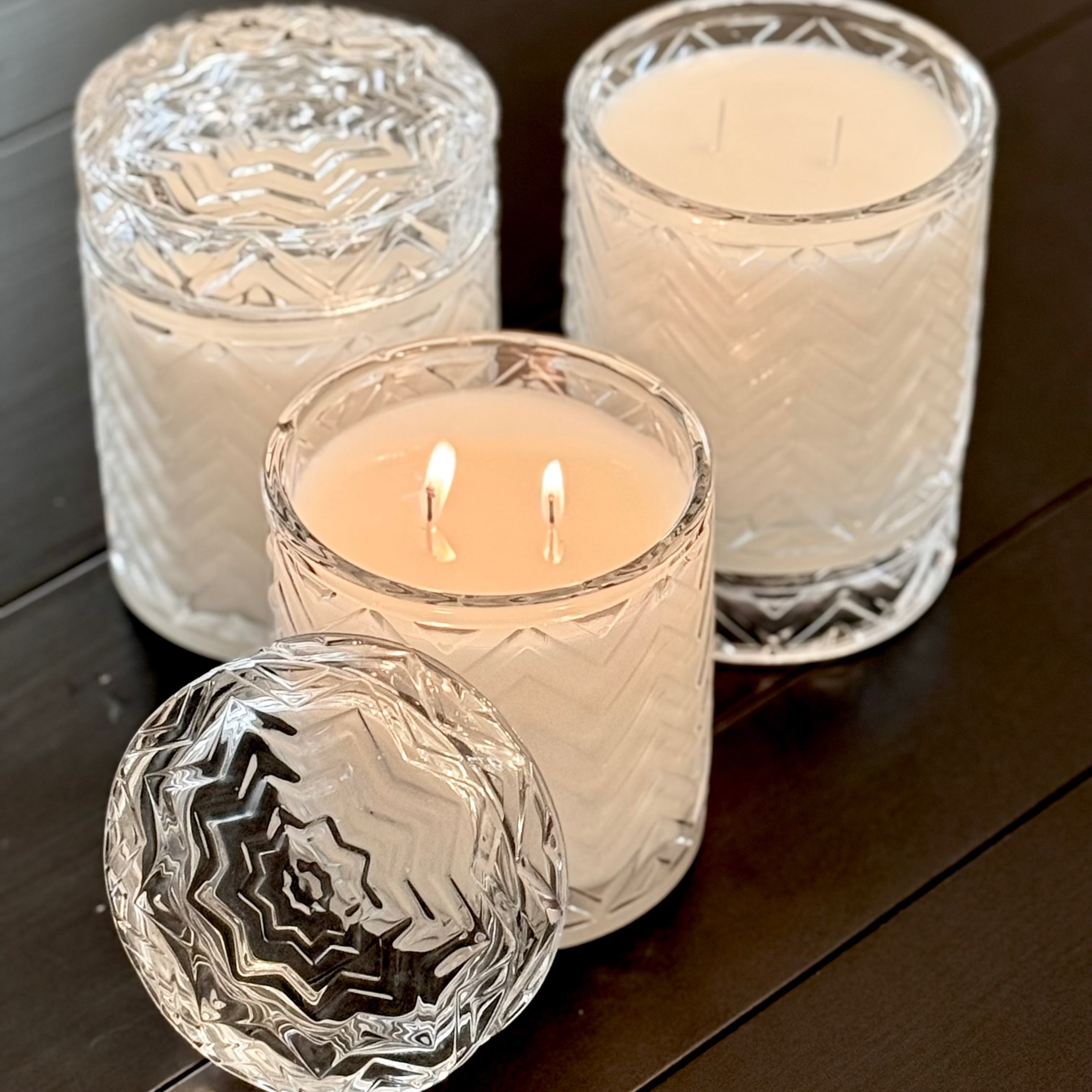 Three lit candles in glass holders on a wooden surface