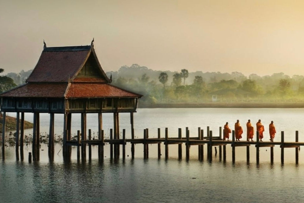 Mahogany hut on stilts over water with people walking along the pier representing Woodland & Mahogany Teak scent