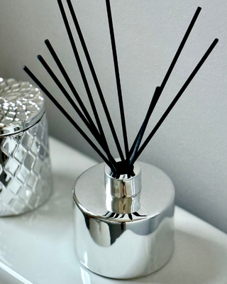 Silver diffuser with black reeds on a white surface