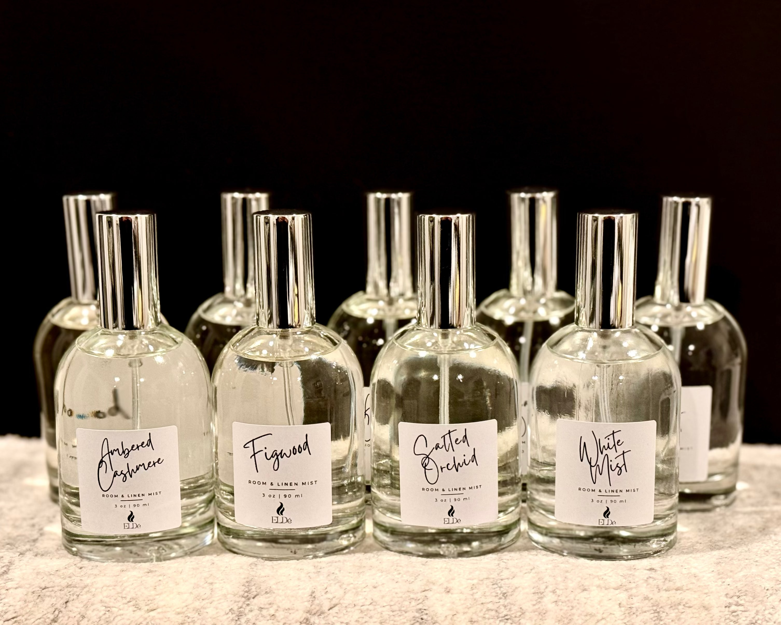 Set of clear glass bottles with labels on a textured surface