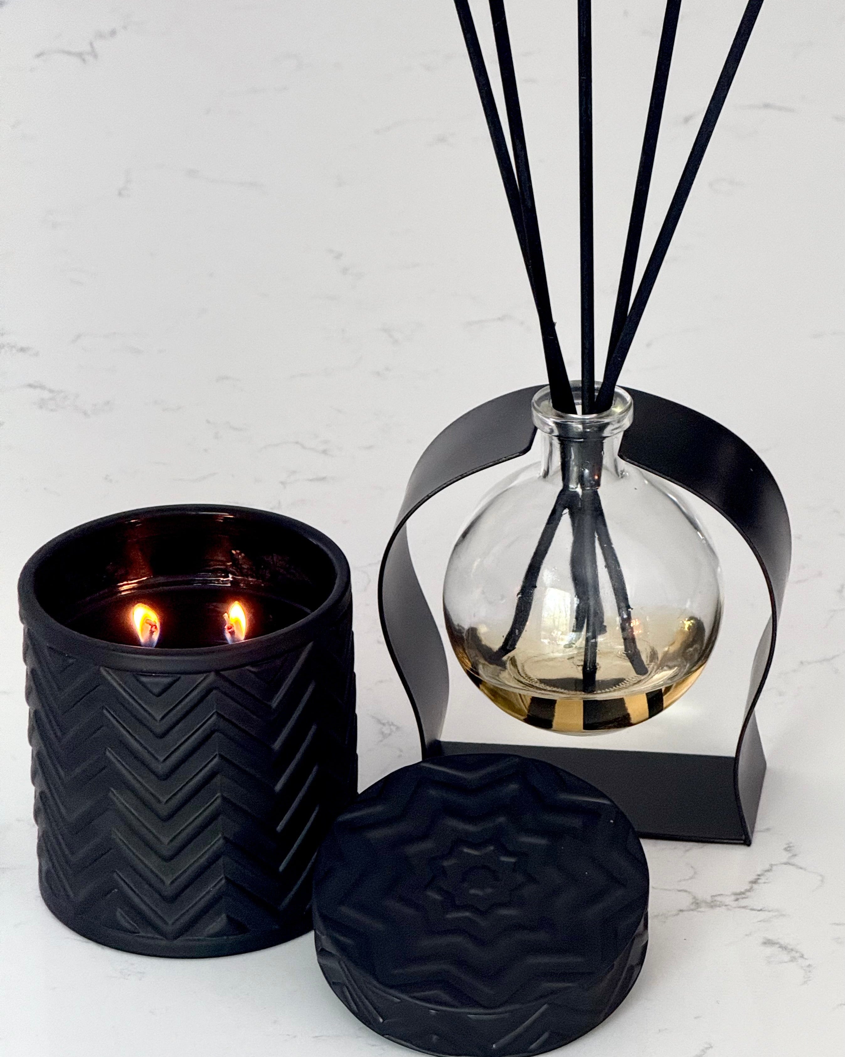 Black textured candle and diffuser on a white marble surface