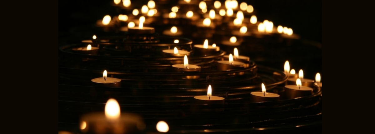 Row of lit candles in a dark setting