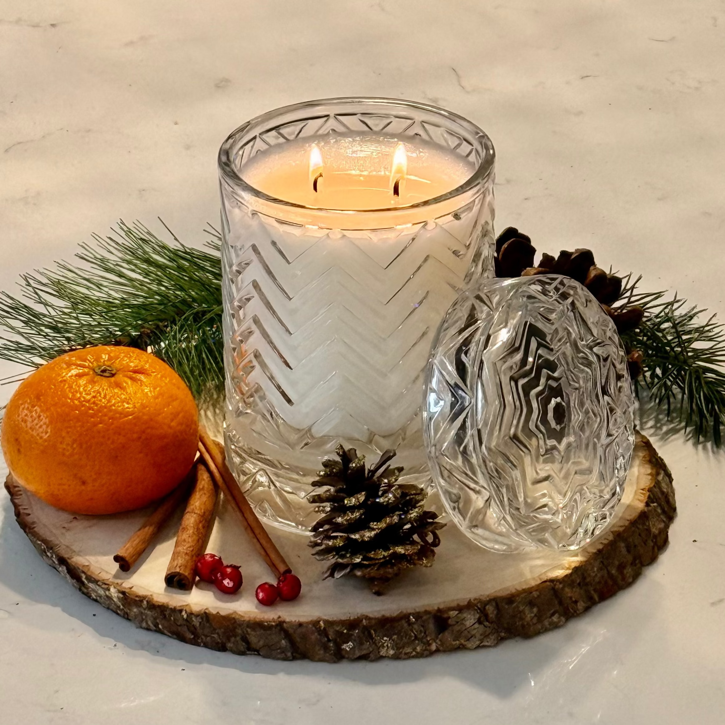 Candle in a glass holder with decorative elements on a white surface