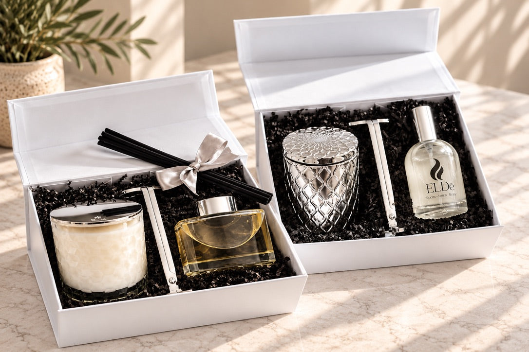 ELDé HexaGlow and SilverScape Gift Sets displayed in open white gift boxes, featuring candles, an Eclipse reed diffuser, Room • Linen • Body Mist, and silver wick trimmers.