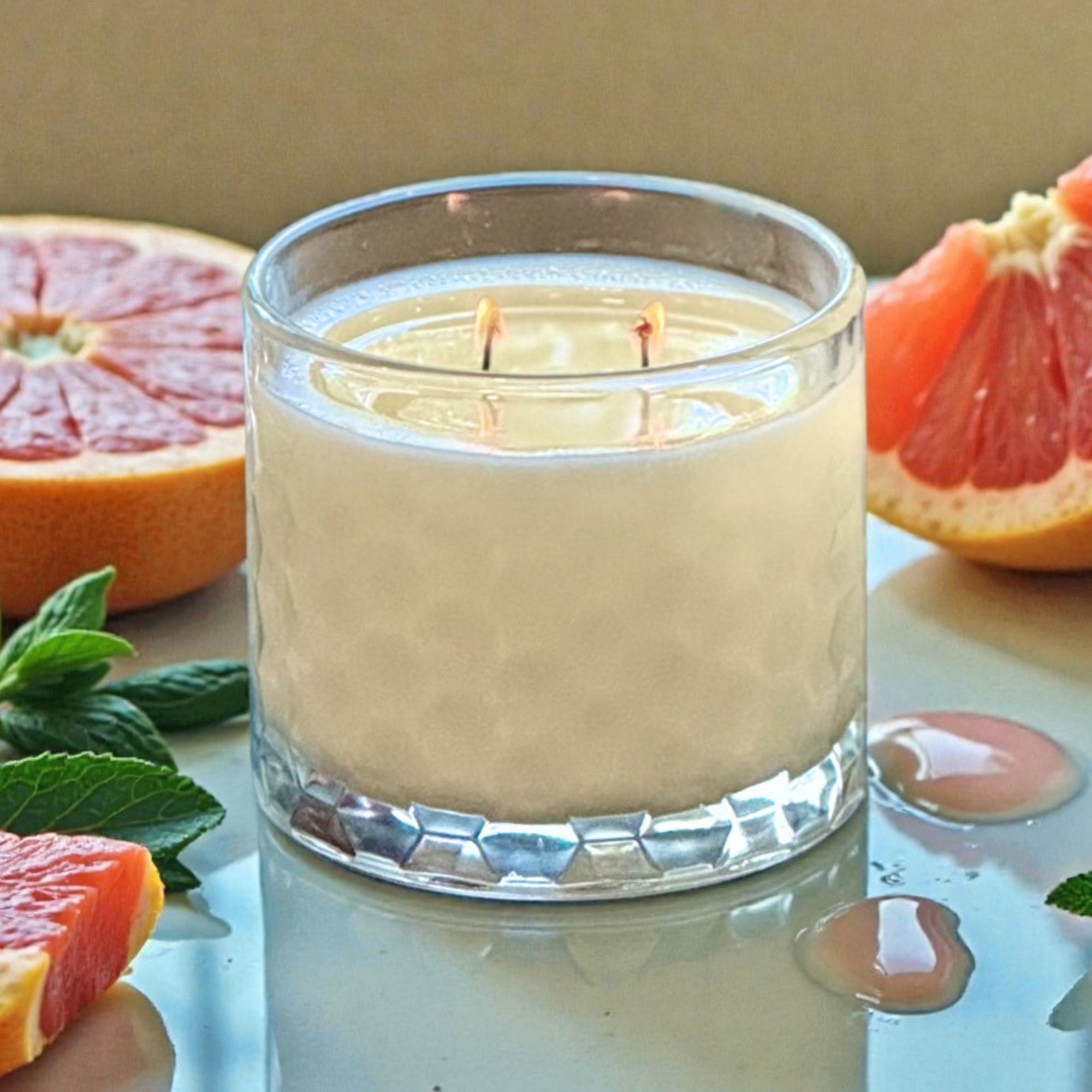 close up of grapefruit scented candle on countertop with cut slices of grapefruit