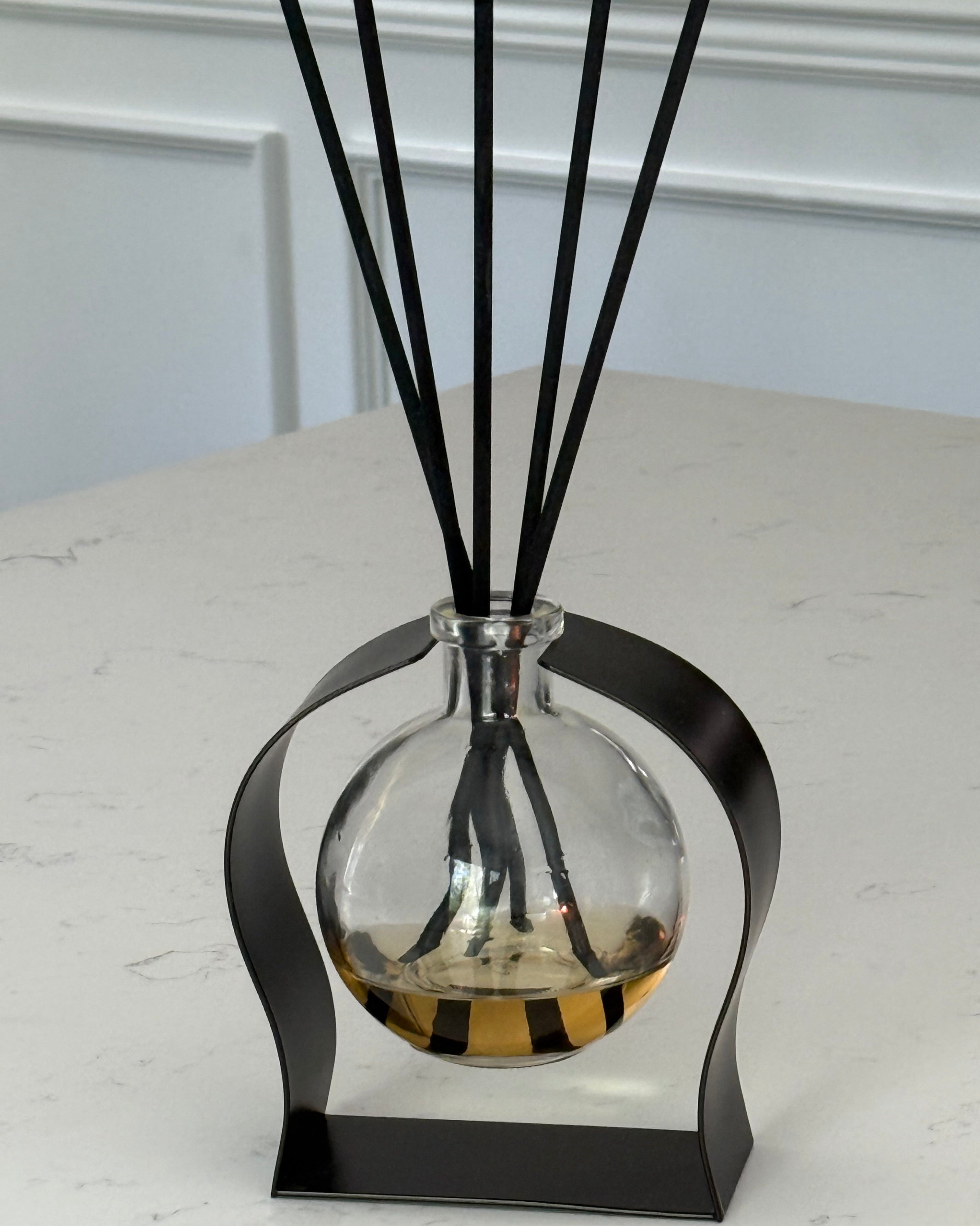 Decorative diffuser with black and gold oil on a white wall.