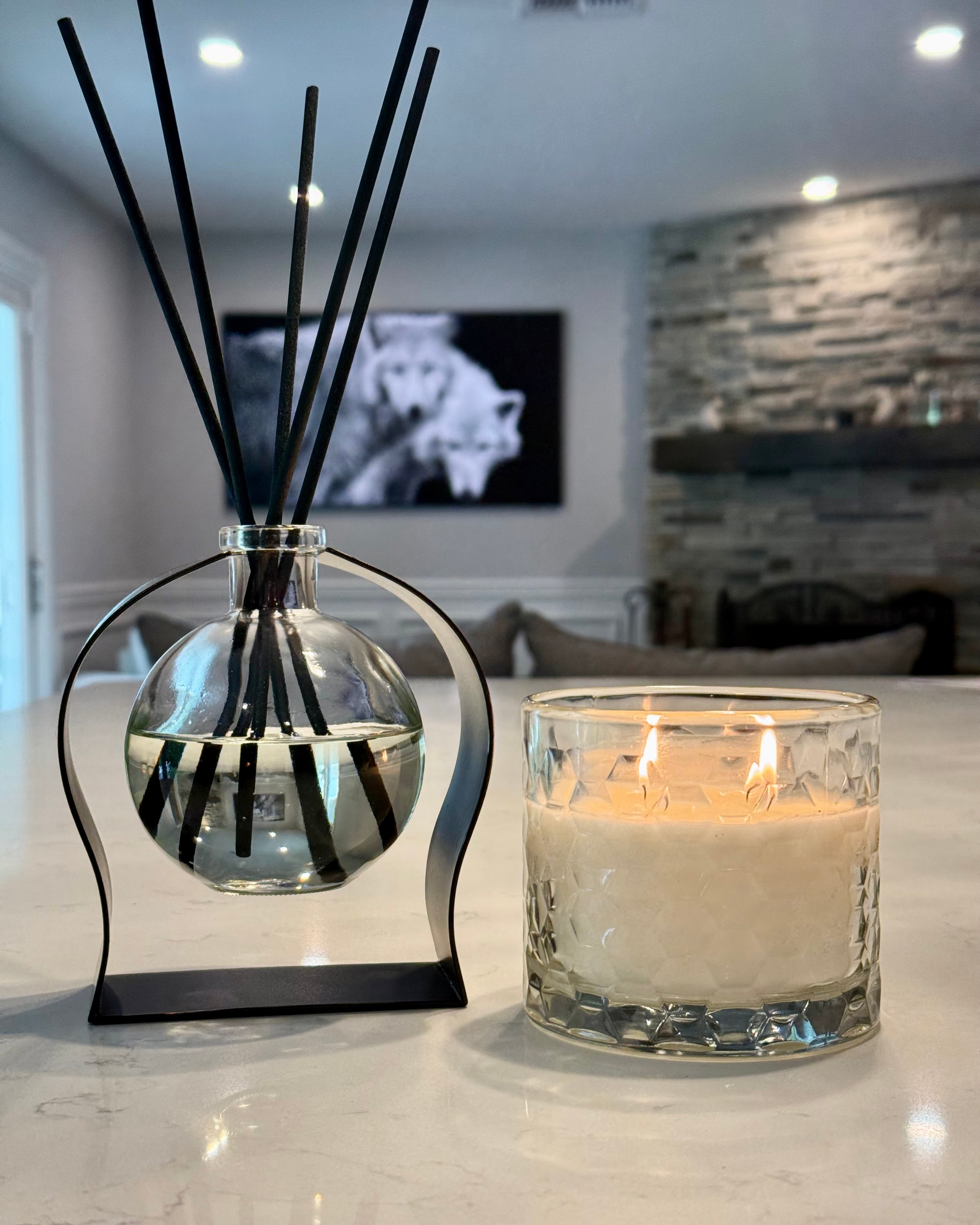 Diffuser with black sticks and a candle on a surface in a room.